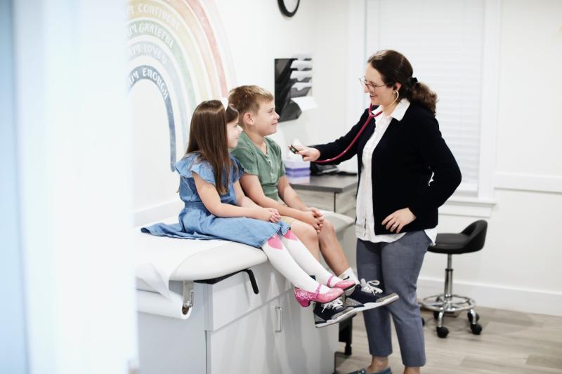 a doctor examining two children on an exam table