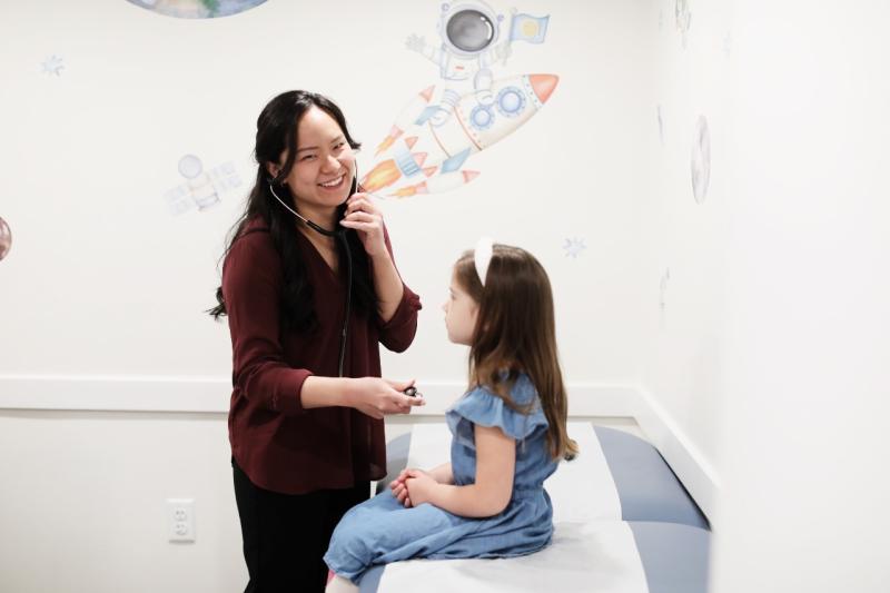 a doctor listening to the heart of a young girl